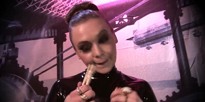 Dominatrix dressed in latex is playing with a toy