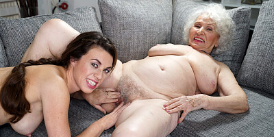 Smiley brunette Tiffany Doll pleasures busty granny on the sofa