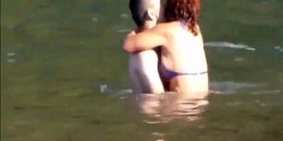 Horny couple having some fun in the water at the beach