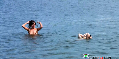 Nude beach girl sunbathes next to her man outdoors
