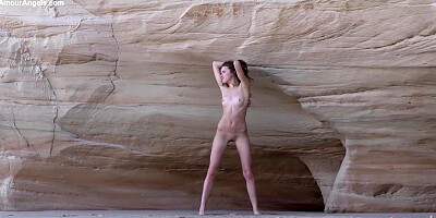 Slender teenager black-haired is posing naked near the rocks and opening up up broad to demonstrate her vag