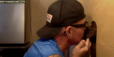 Inked DILF sucks black cock in gloryhole till cum in mouth