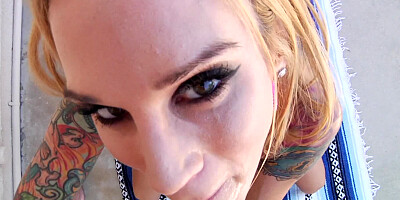 A blonde that has ink all over her body is getting cumshot in face