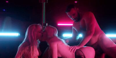 Two blondes take turns on a stud under neon lights