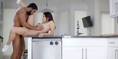 A busty brunette is on top of the kitchen sink, getting fucked