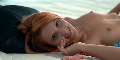 A wet and kinky redhead is alone on the bed, teasing her wet pussy lips