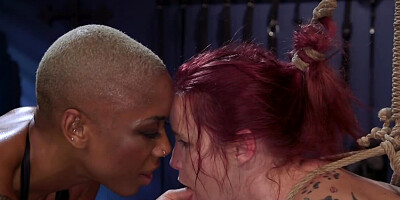 Ebony domme in leather top turns the redhead into her slave
