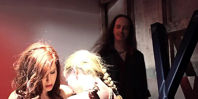 Two busty women are giving a BJ in front of a crowd