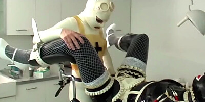 One girl is bound in latex as the other one strap-on fucks her