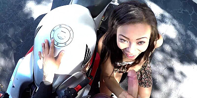 A skinny ebony girl is getting naked outside next to a bike