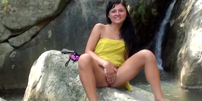 Brunette Bella Margo poses naked by the waterfall and masturbates