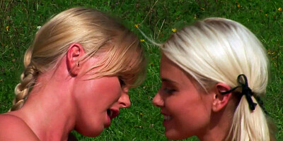 Two ladies sitting on the grass, playing with their sex toys