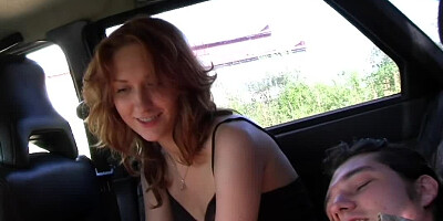 A redhead is on her knees outside, sucking two large dicks