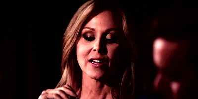 A blonde is having a romantic dinner with her lover in the dark