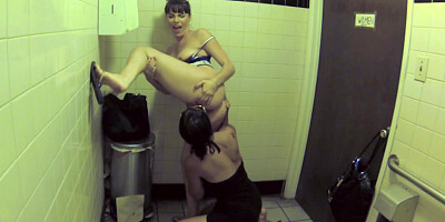 Two bitches are in the public bathroom, licking one another