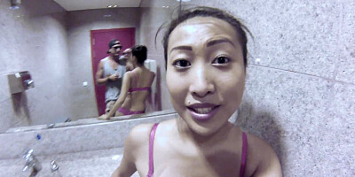 Asian woman with large natural boobs is fucking a dude in the bathroom