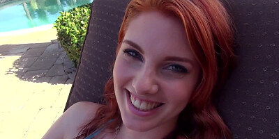 Redhead in blue bikini gives a blowjob looking into man's eyes