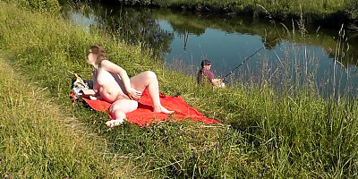Naked mature woman is filmed while sunbathing by the river