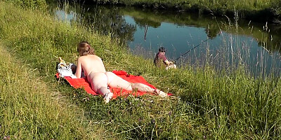 Naked mature woman is filmed while sunbathing by the river