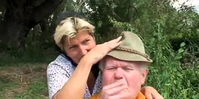 A blond girl washes herself by the river and two old men are watching her