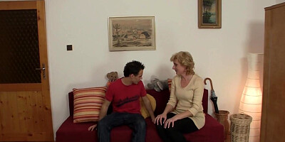 Blonde GILF talks on the couch next to a slender lad