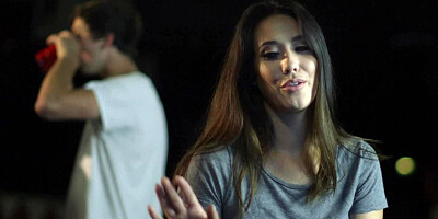 Two sexy women are in front of a crown in a bar, licking each other