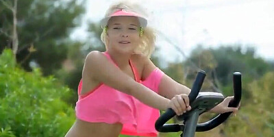 Petite blonde teen rides a stationary bike outdoors while being totally naked