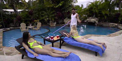 Two sex-craving girls are sharing a fat cock in a threesome next to a pool